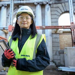 employee of belfour beatty with a construction site in the background